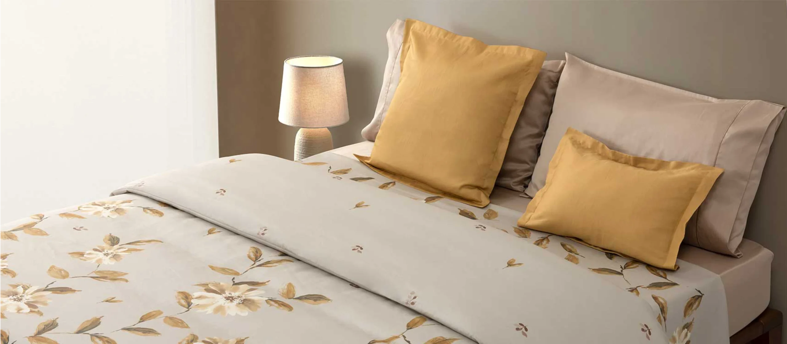 Cama com conjunto de roupa de cama em tons de bege, com estampa floral em amarelo e almofadas lisas amarelas da RIFER